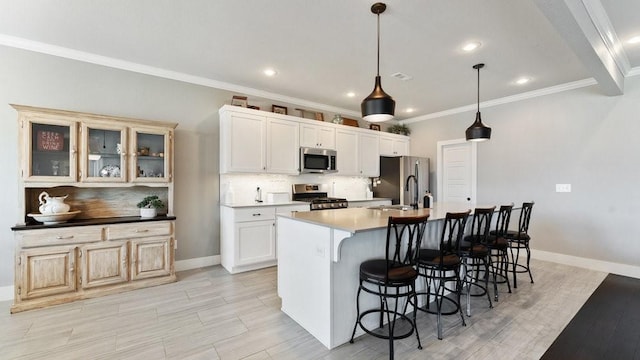 kitchen featuring stainless steel appliances, backsplash, an island with sink, pendant lighting, and ornamental molding