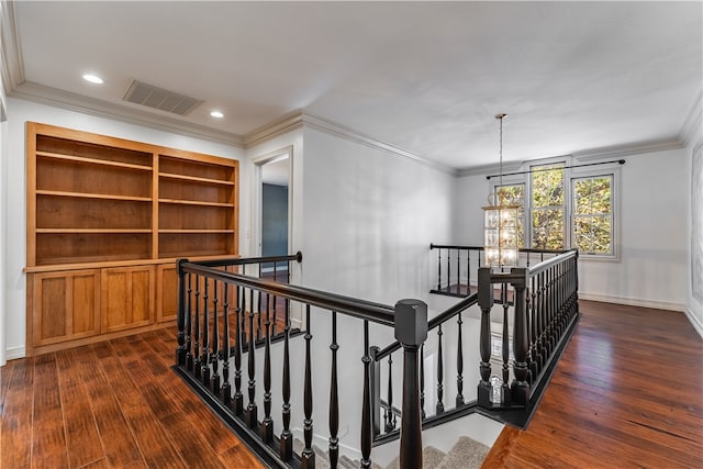 corridor with dark wood-type flooring, crown molding, and an inviting chandelier