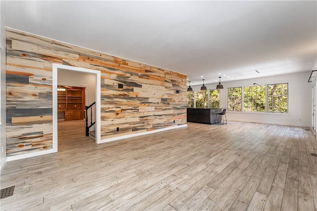 unfurnished living room with light hardwood / wood-style flooring and wood walls