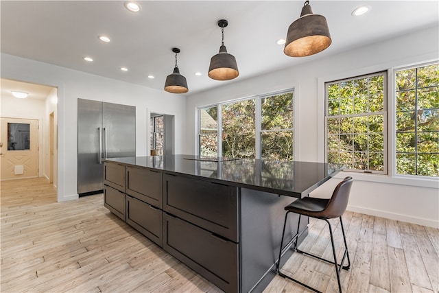 kitchen featuring light hardwood / wood-style floors, stainless steel built in refrigerator, a kitchen island, and pendant lighting