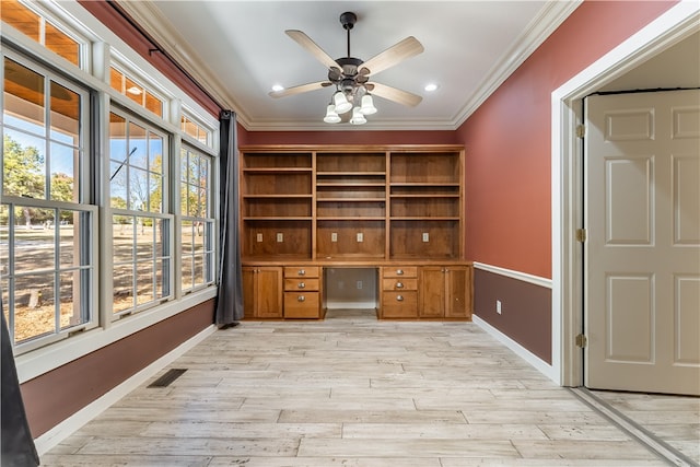 unfurnished office featuring built in desk, light wood-type flooring, a healthy amount of sunlight, and ceiling fan