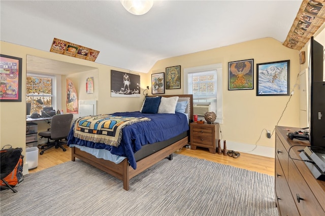 bedroom featuring light wood-type flooring, lofted ceiling, and baseboards