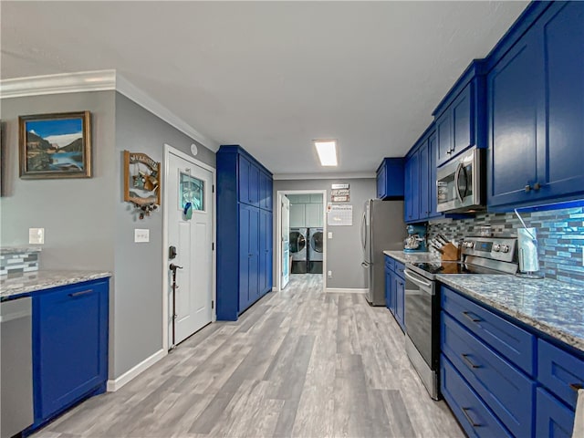 kitchen with blue cabinetry, appliances with stainless steel finishes, washer and clothes dryer, and backsplash