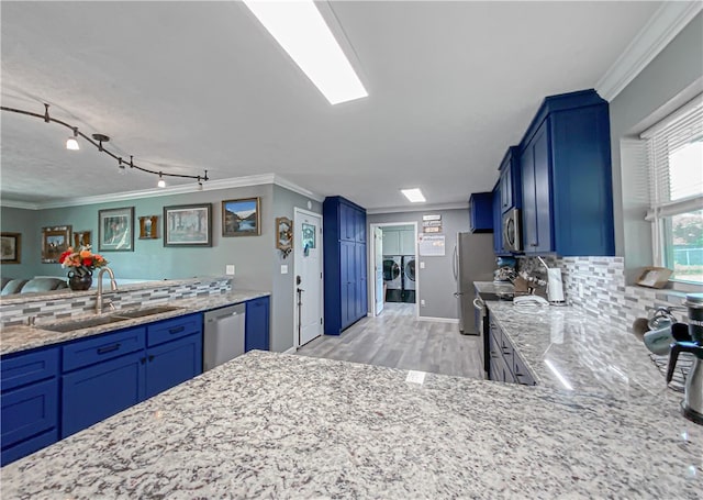 kitchen featuring appliances with stainless steel finishes, light wood-type flooring, independent washer and dryer, ornamental molding, and sink