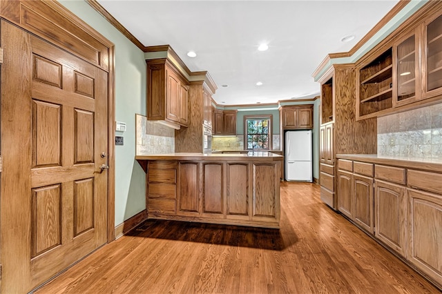 kitchen with kitchen peninsula, decorative backsplash, dark wood-type flooring, and white refrigerator