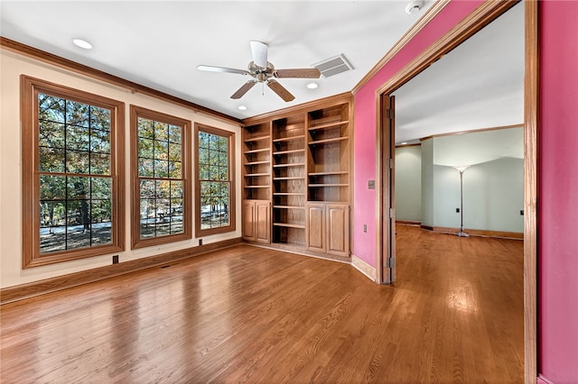 empty room featuring crown molding, wood-type flooring, and ceiling fan