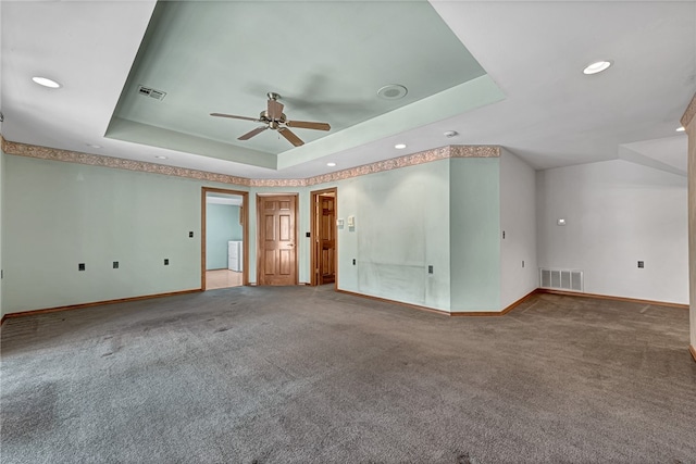 spare room with carpet flooring, a tray ceiling, and ceiling fan