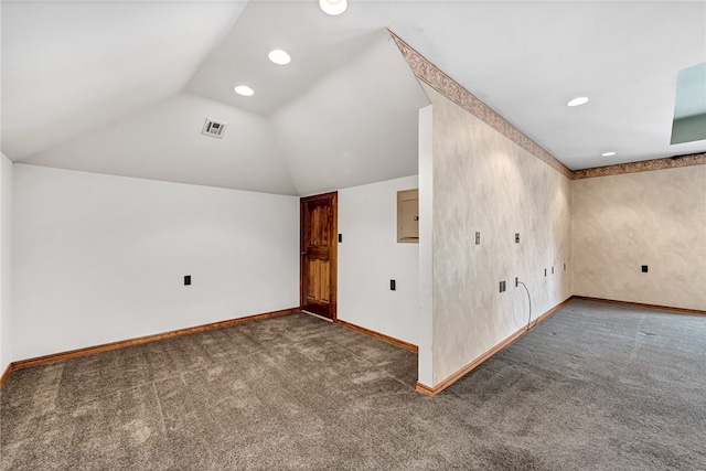 bonus room with dark carpet and vaulted ceiling