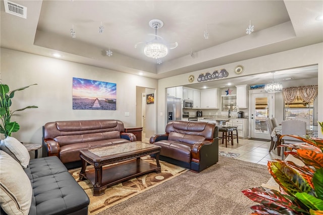 tiled living room featuring a notable chandelier and a tray ceiling