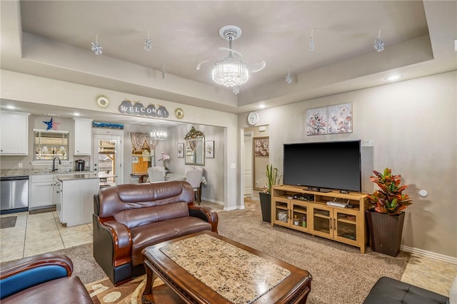 living room with light carpet, a notable chandelier, sink, and a raised ceiling