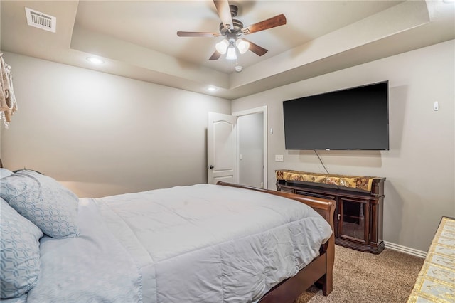 carpeted bedroom featuring ceiling fan and a raised ceiling