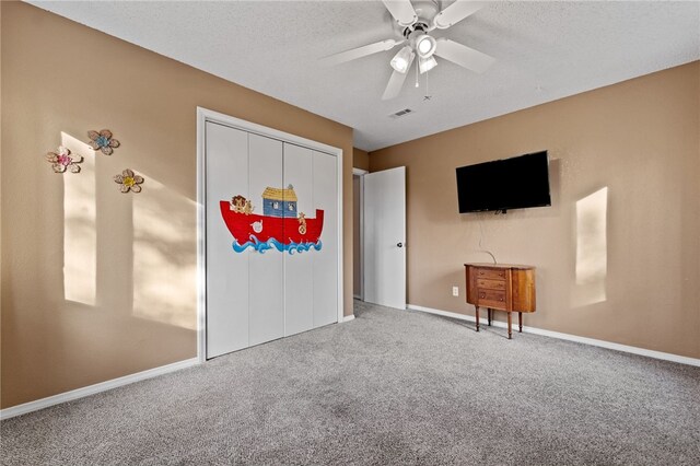 interior space with ceiling fan, a textured ceiling, and carpet