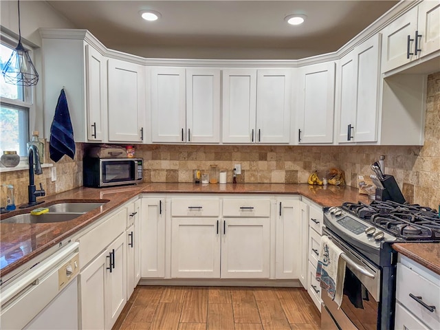 kitchen with sink, white cabinetry, hanging light fixtures, and stainless steel appliances