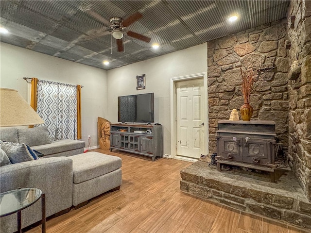 living room with light hardwood / wood-style flooring, a wood stove, and ceiling fan