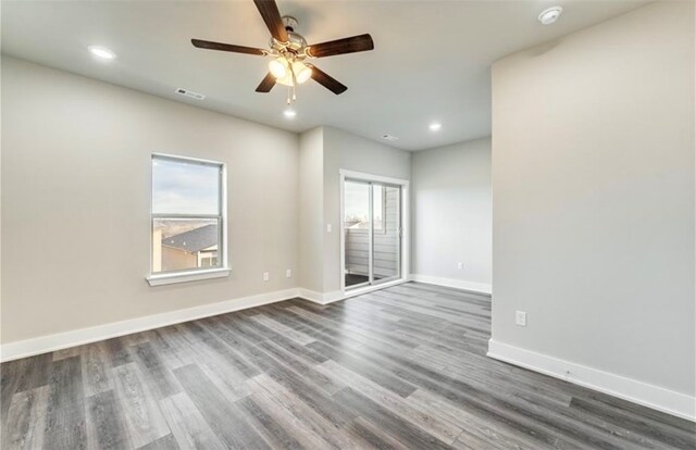 spare room with ceiling fan, a healthy amount of sunlight, and dark hardwood / wood-style flooring