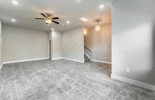 spare room featuring ceiling fan with notable chandelier