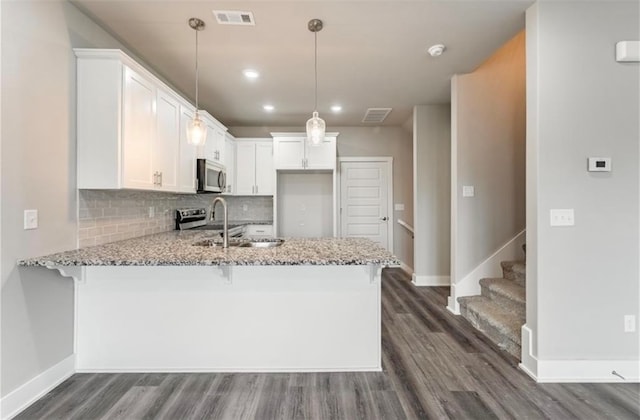 kitchen featuring kitchen peninsula, white cabinets, decorative light fixtures, and dark hardwood / wood-style flooring