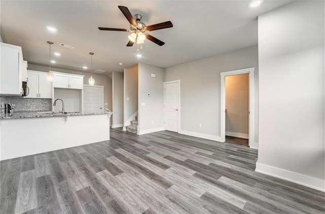 kitchen featuring dark wood-type flooring, hanging light fixtures, white cabinets, light stone counters, and tasteful backsplash