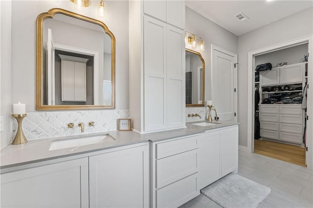 bathroom featuring double vanity, a sink, visible vents, and a walk in closet