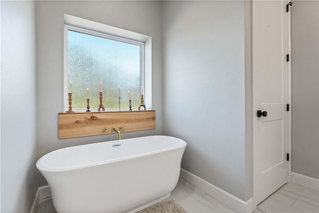 full bathroom with a freestanding bath and baseboards