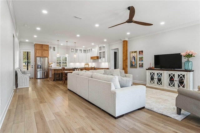 living area featuring light wood finished floors, baseboards, ornamental molding, and recessed lighting