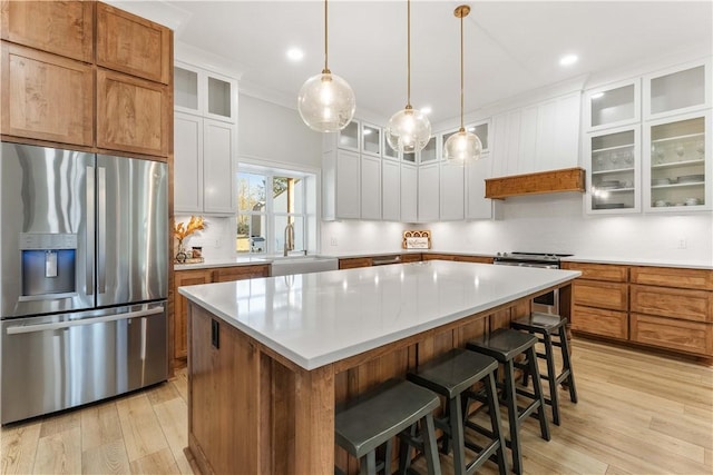 kitchen featuring appliances with stainless steel finishes, a sink, light wood finished floors, and a kitchen island