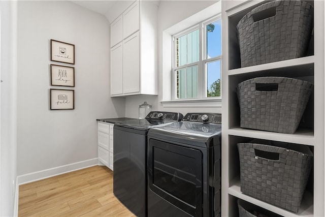 washroom with cabinet space, baseboards, light wood finished floors, and washing machine and clothes dryer