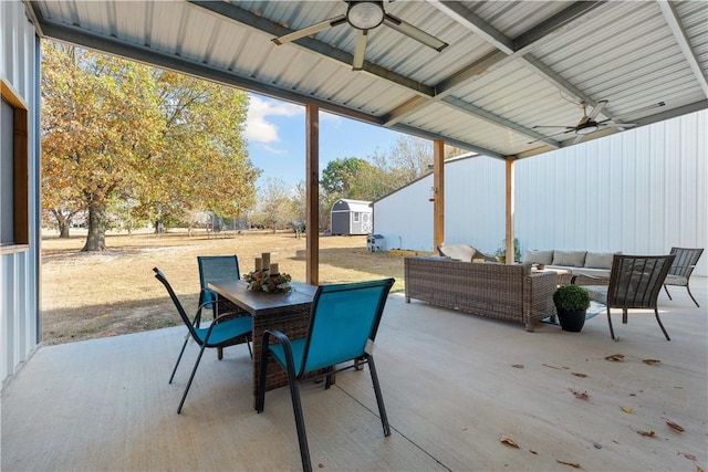 view of patio / terrace featuring ceiling fan, an outdoor hangout area, outdoor dining area, an outdoor structure, and a shed