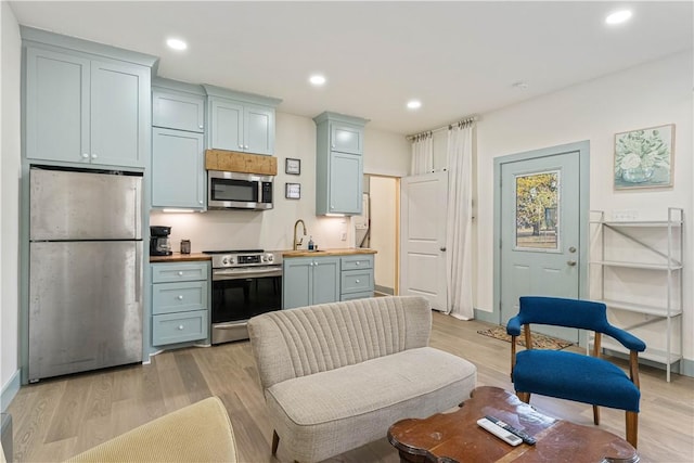 kitchen featuring light wood-style flooring, recessed lighting, a sink, wooden counters, and appliances with stainless steel finishes