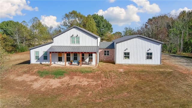 rear view of property featuring metal roof, a yard, board and batten siding, and a standing seam roof