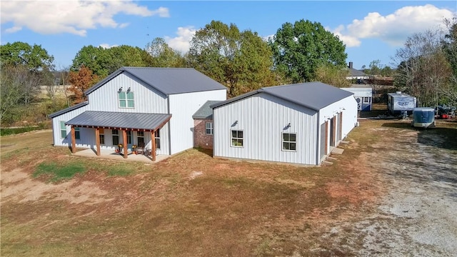 rear view of property featuring metal roof, a patio area, and driveway