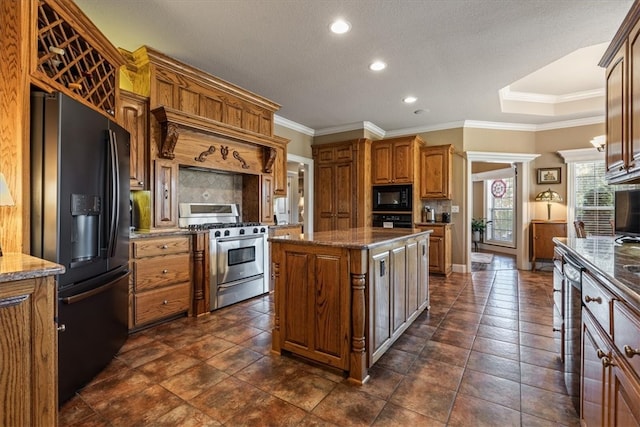 kitchen with decorative backsplash, crown molding, black appliances, and a kitchen island