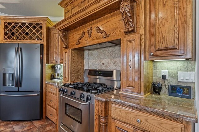 kitchen featuring decorative backsplash, appliances with stainless steel finishes, dark tile patterned floors, and dark stone countertops