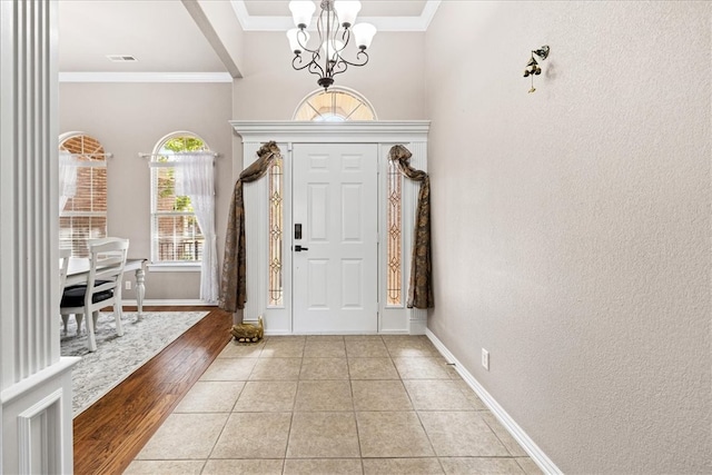 entryway with light wood-type flooring, crown molding, and a chandelier