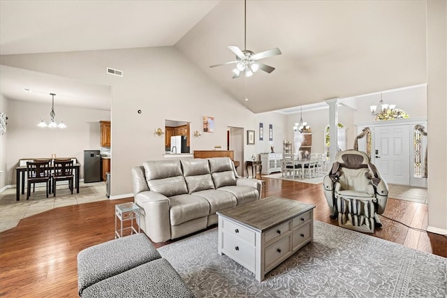 living room with ceiling fan, ornate columns, high vaulted ceiling, and light hardwood / wood-style flooring