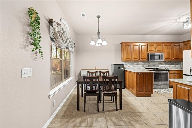 kitchen with hanging light fixtures, decorative backsplash, light tile patterned floors, appliances with stainless steel finishes, and a chandelier