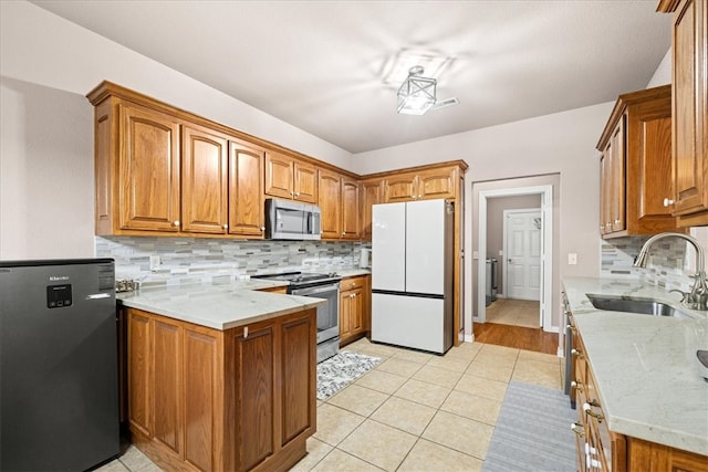 kitchen featuring backsplash, light stone counters, sink, and appliances with stainless steel finishes