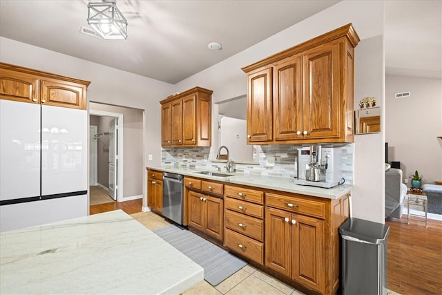 kitchen featuring sink, tasteful backsplash, stainless steel dishwasher, lofted ceiling, and light wood-type flooring