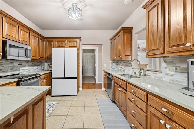 kitchen featuring sink, decorative backsplash, light tile patterned floors, light stone counters, and stainless steel appliances