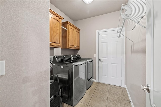 clothes washing area featuring cabinets, independent washer and dryer, and light tile patterned floors