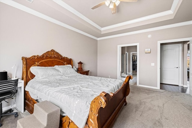 carpeted bedroom with a tray ceiling, ceiling fan, and ornamental molding