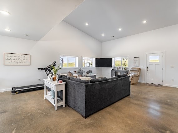 living room featuring concrete flooring, high vaulted ceiling, and plenty of natural light