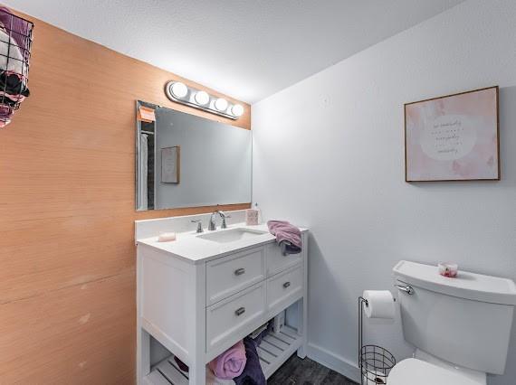 bathroom with toilet, vanity, and wood-type flooring