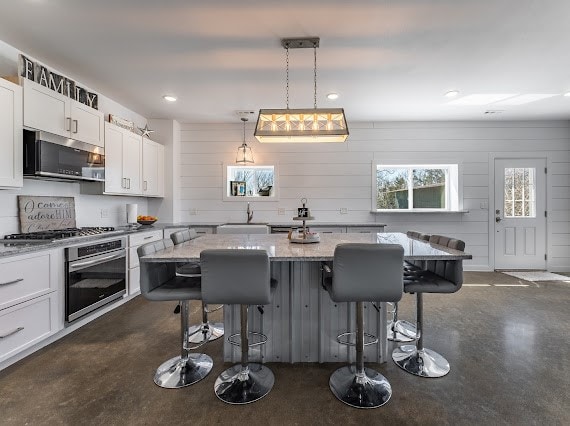 kitchen featuring a breakfast bar, light stone countertops, stainless steel appliances, and hanging light fixtures