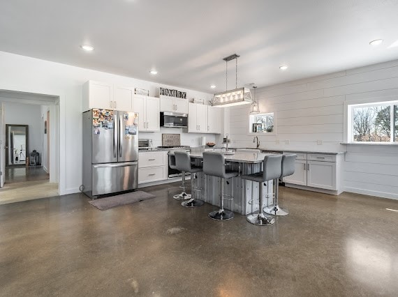 kitchen featuring hanging light fixtures, a center island, a kitchen bar, white cabinetry, and appliances with stainless steel finishes