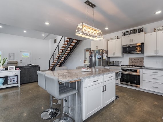 kitchen with appliances with stainless steel finishes, white cabinetry, and a center island