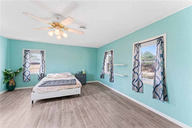 bedroom with multiple windows, light wood-type flooring, and ceiling fan