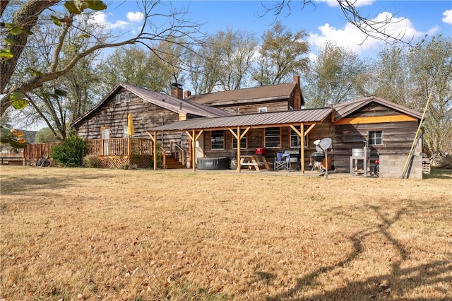 18405 Rheas Community Rd, Lincoln, AR 72744 - back of property featuring a hot tub, a lawn, a wooden deck, a chimney, and metal roof
