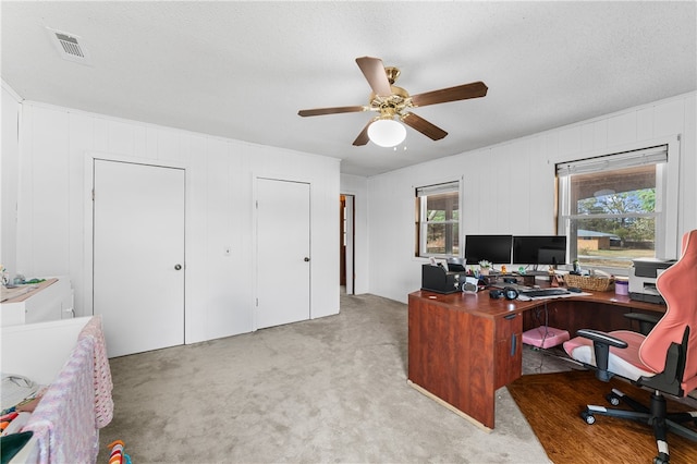 carpeted office with a textured ceiling, plenty of natural light, and ceiling fan