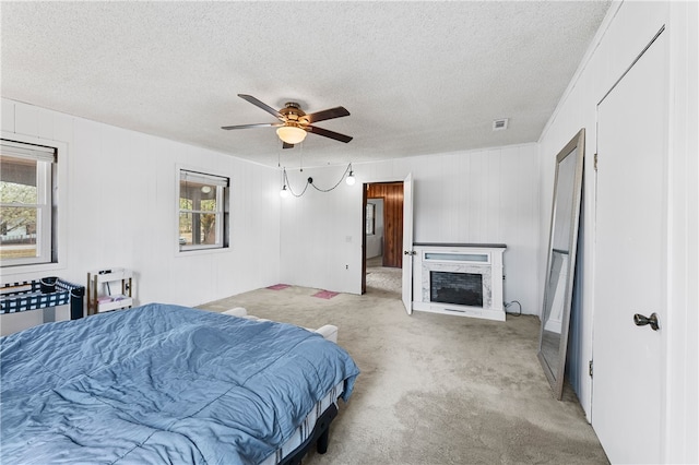 carpeted bedroom with ceiling fan and a textured ceiling